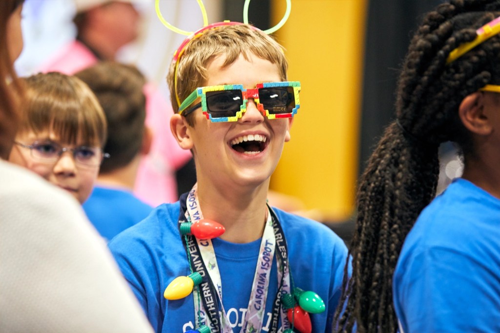 A kid smiling while wearing LEGO sunglasses