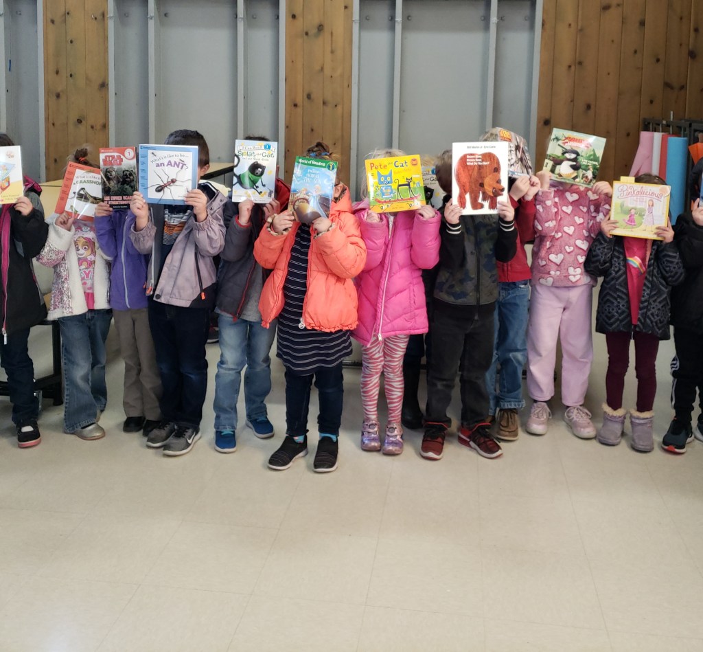 A group of children holding up books over their heads