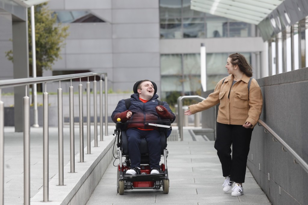 Two people traveling over a bridge through Meath, Ireland - one on foot and the other in a wheelchair