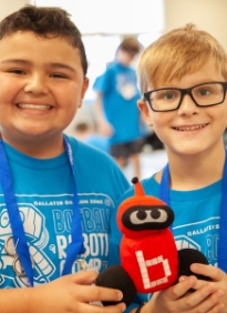 Two boys holding up a plush robot