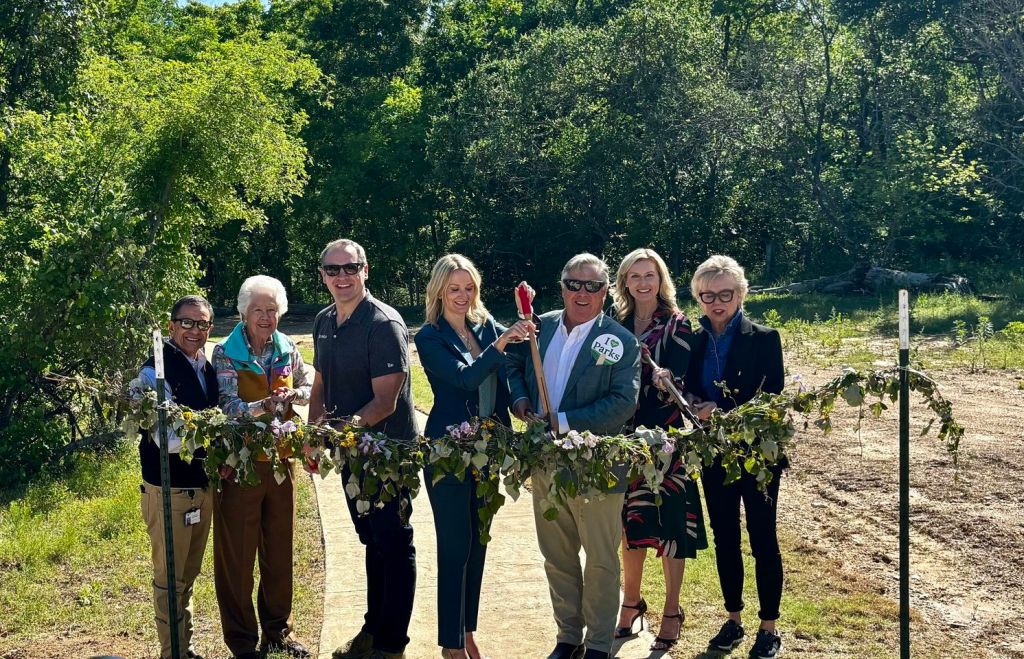 A group of people cutting a leaf-ribbon