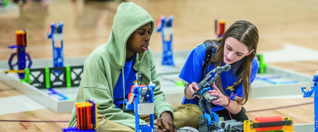 Left to right: a bout and a girl building a LEGO robot.