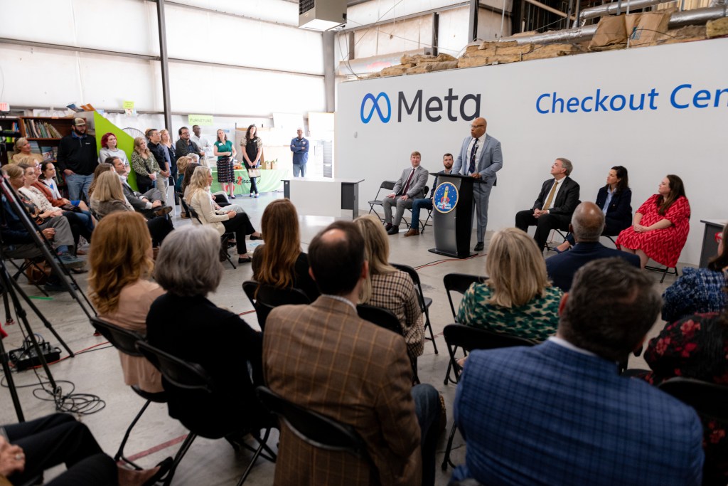 A group of people in front of a Meta branded wall